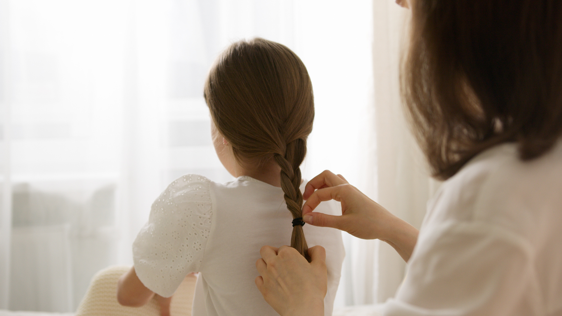 Woman in White Dress Shirt Braiding a Girl's Hair